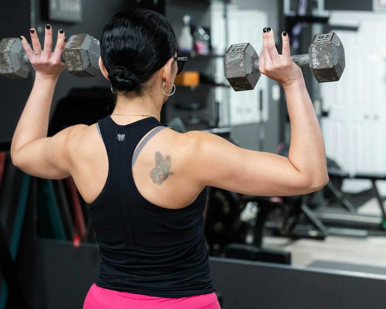 Maigrir des bras : femme réalisant un exercice de renforcement des bras avec deux haltères