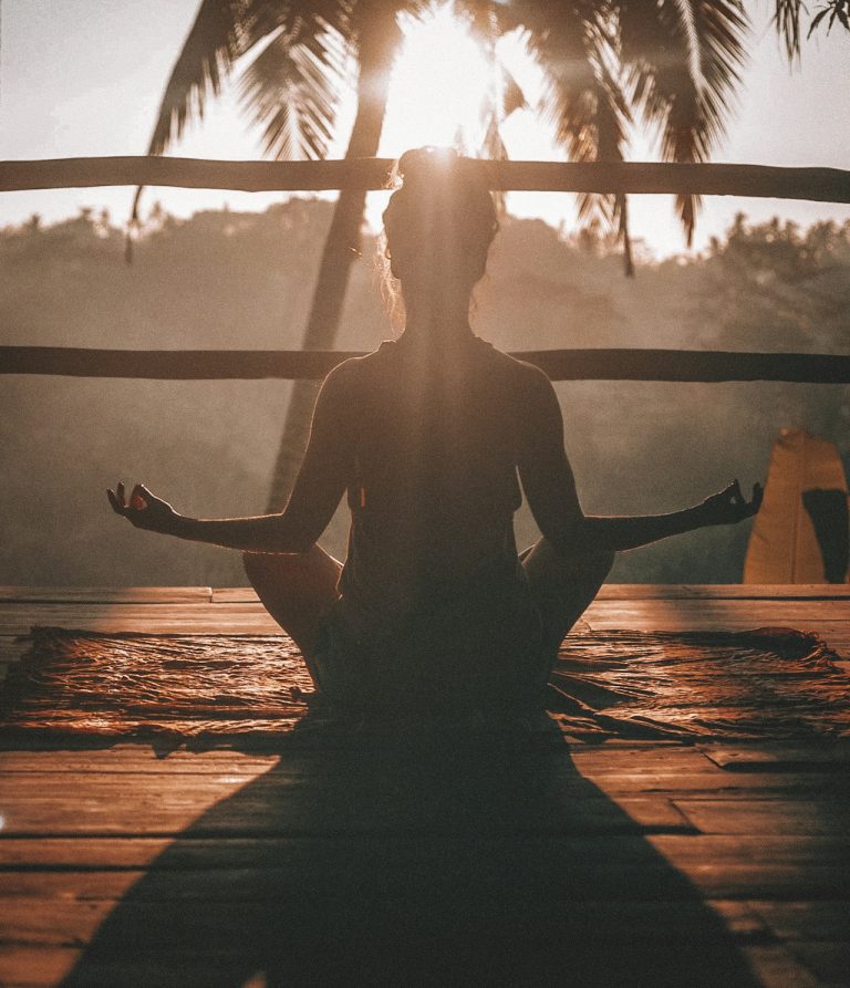 Méditation pour débutant : femme en posture de méditation au coucher du soleil