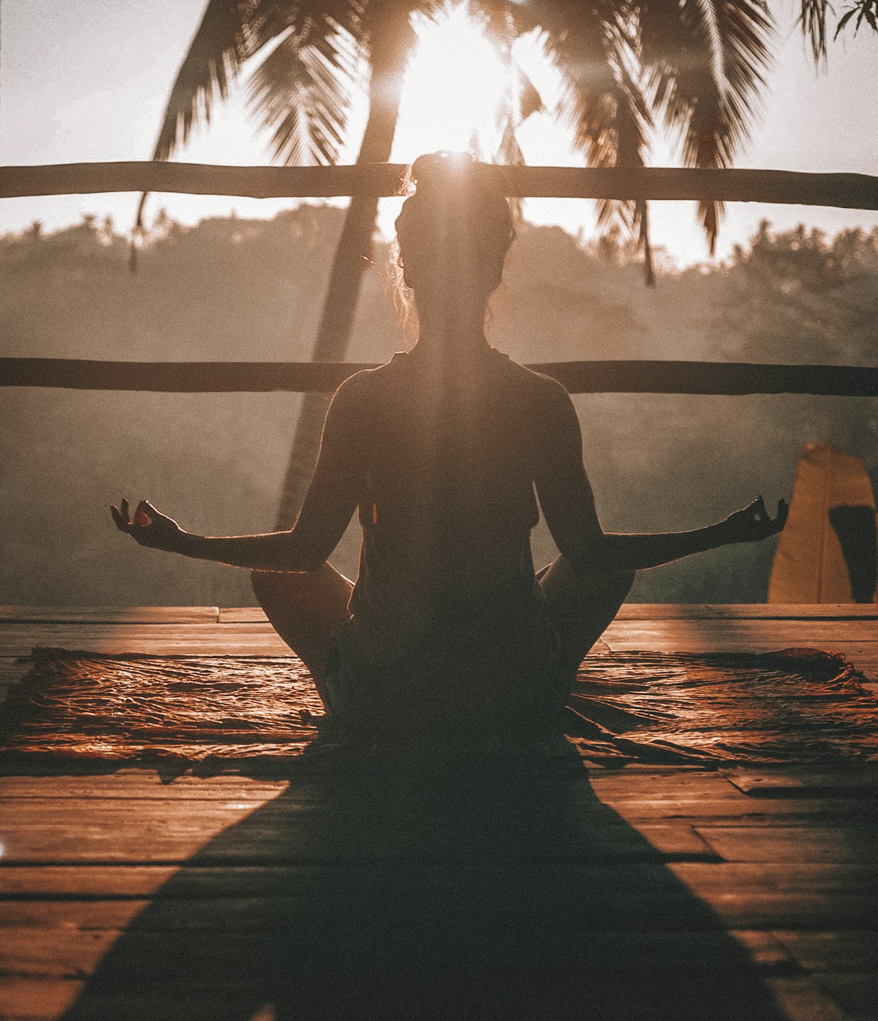 Méditation pour débutant : femme en posture de méditation au coucher du soleil