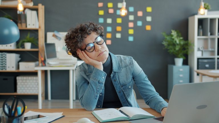 Femme épuisée au travail tête posée sur la main — symptômes burn out