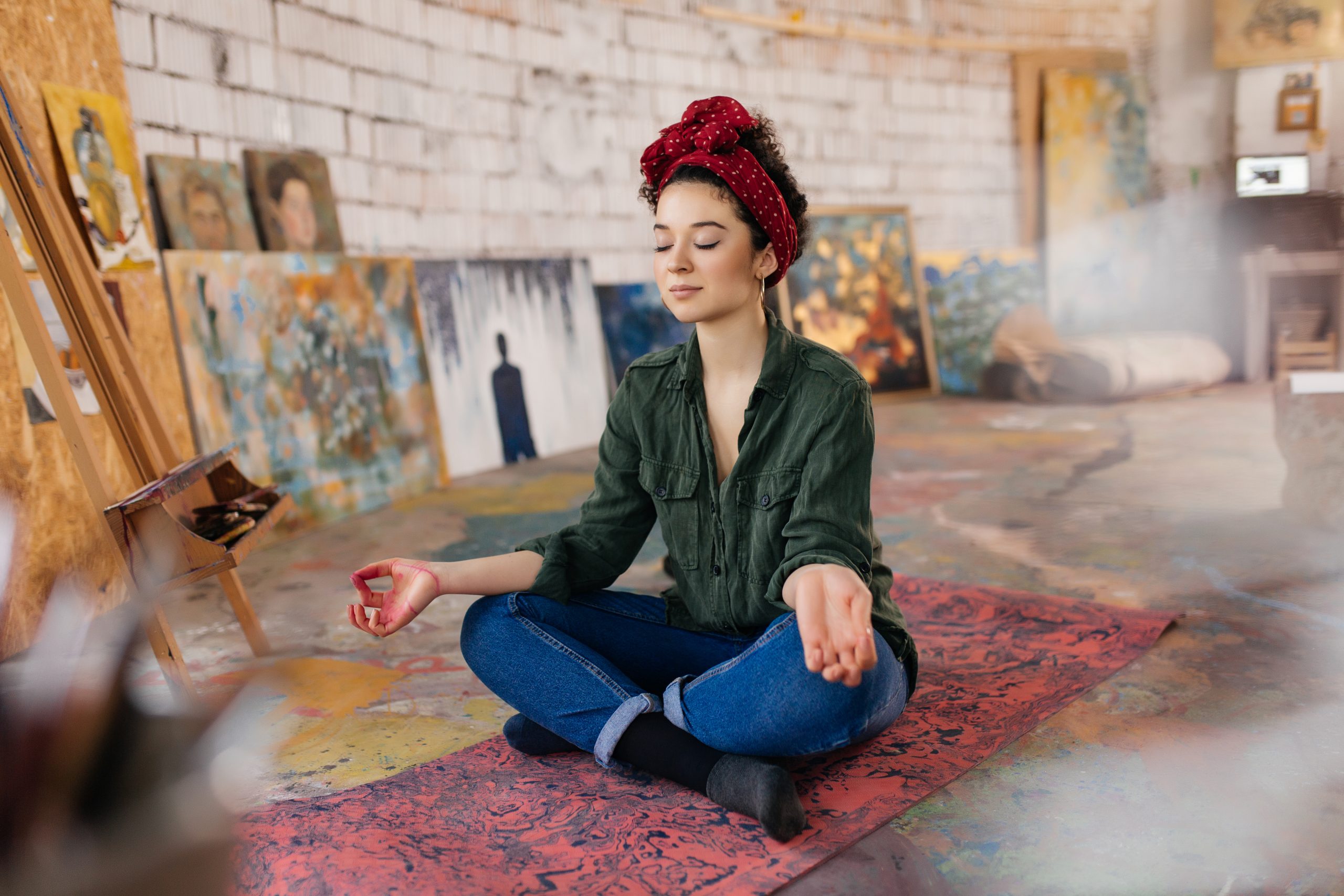 Jeune femme méditant dans un atelier artistique, symbole de créativité, sérénité et bien-être.