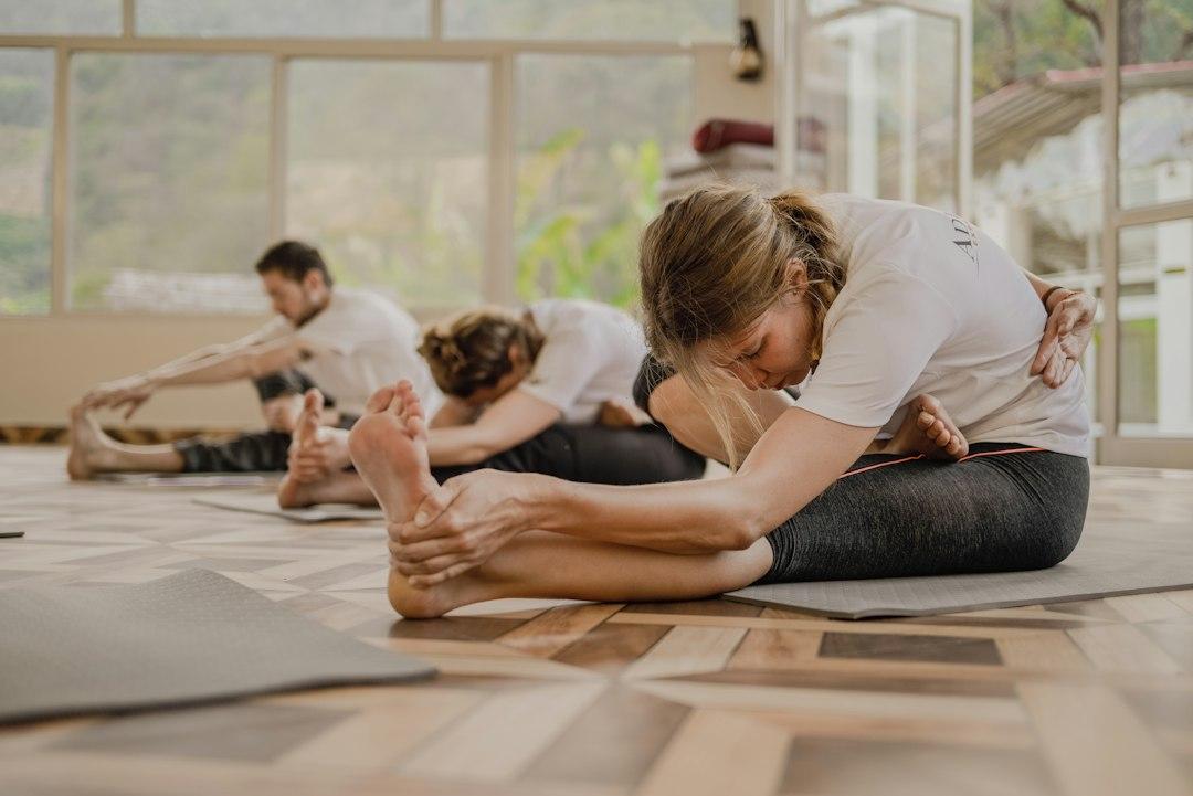 Élèves en flexion avant assise pendant un cours de yoga, chacun à son niveau