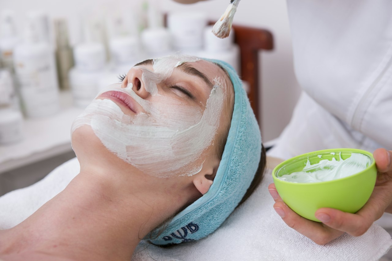 Peeling visage : application professionnelle d'un soin exfoliant sur le visage d'une femme en institut