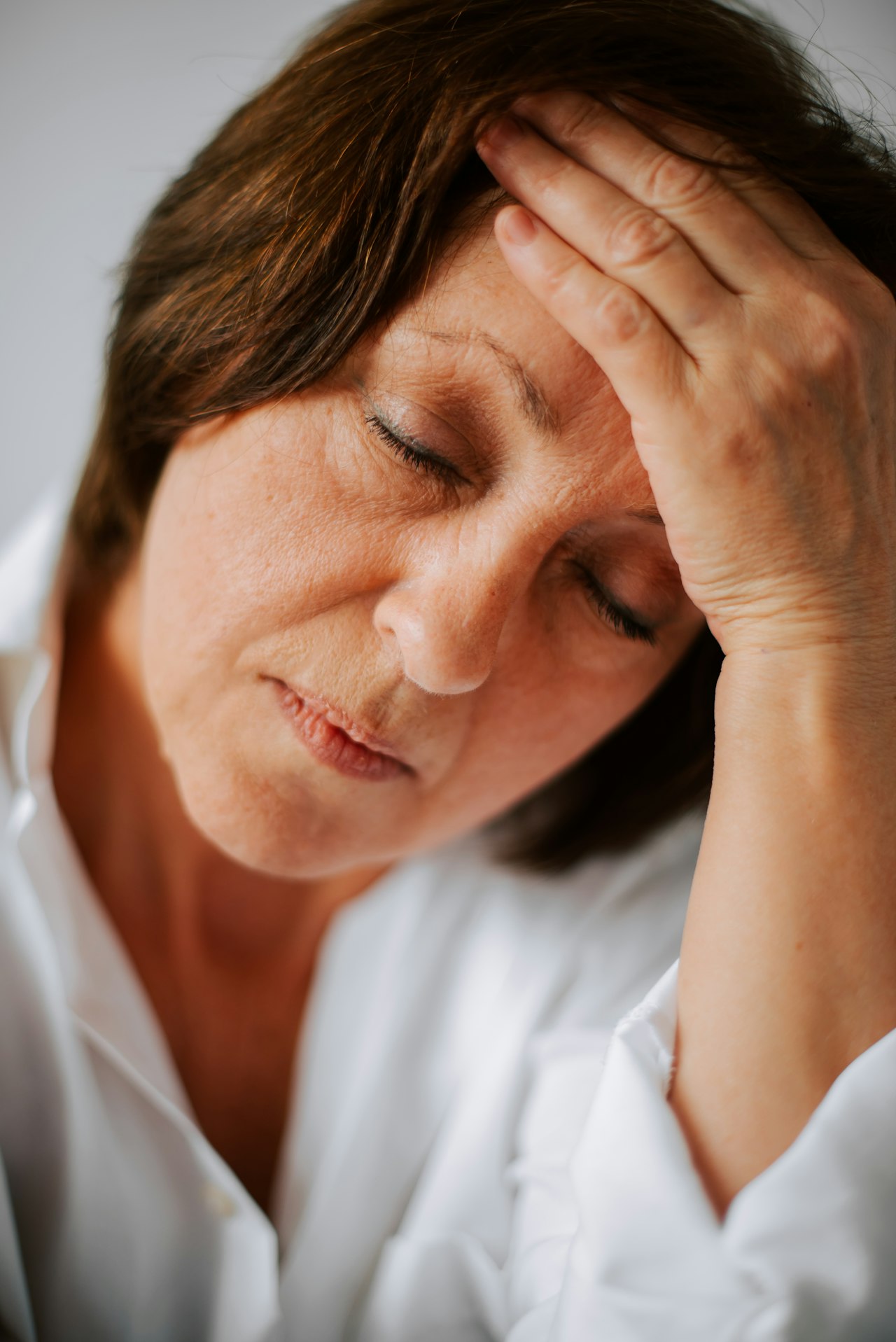 Femme fatiguée se tenant la tête — symptôme fréquent de la thyroïdite de Hashimoto